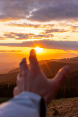 a hand that wants to grab the sun, moments of life, against the background of mountains at sunset, rest in nature with animals, landscape