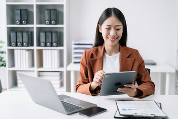 Business women hand working with tablet and laptop computer with documents on office desk in modern office.