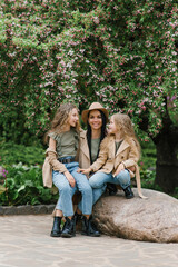 Mom and her two daughters are chatting and walking in park