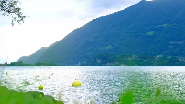 expanse of the blue lake Brienz in Switzerland, the mountains in the background, yellow buoy sways in the water on waves, the concept of sports tourism, weekend hike, active vacation, water sports