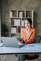 Female asian sitting at the desk, looking to camera.