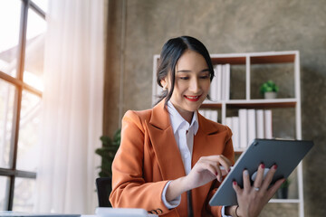 business woman sitting at her desk, reading stats and graphs on paperwork at the office.