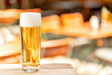 A glass of beer at an outdoor dining space beer garden in summer, text space