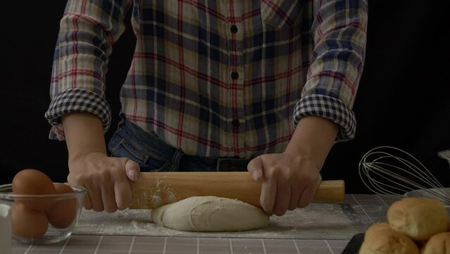 Artisan bread working with dough. Flour dusting on dough, handmade bread dough rolling and kneading in kitchen with bakery equipment tools, black background. professional baker process at work. 60fps