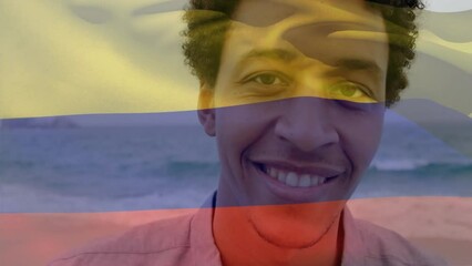 Animation of flag of colombia waving over smiling african american man standing against sea - Powered by Adobe