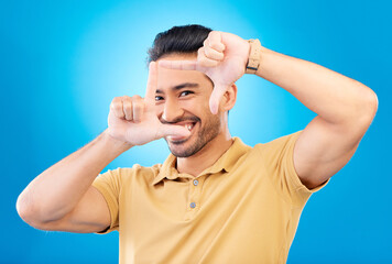 Asian Man, smile and frame hands in portrait for perspective in blue background for photography. Happy male, face and finger framing for creativity in profile with hand out in studio is excited.