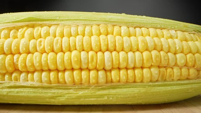 In a mesmerizing macro video, sweetcorn glistens with droplets of water, each tiny sphere reflecting a world of its own. Nature's artistry unveiled. Sweetcorn background. 4K UHD
