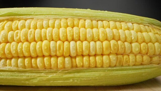 Macro video captures the beauty of sweetcorn, glistening with droplets of water. The intricate details and vibrant colors come alive, offering a tantalizing visual treat. Sweetcorn background
