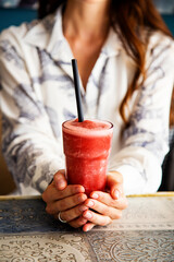 Glass with red berries cocktail smoothie in a woman's hands, vertical  © Yelena