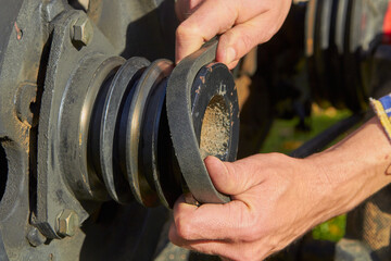 install the belt on the tractor,the hands put the belt on the pulley, the motor drive pulley