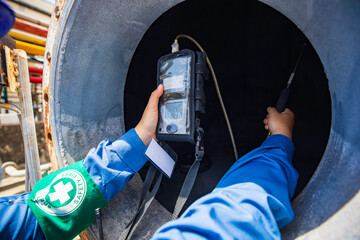 Worker female hand holding gas detector inspection safety gas testing at front manhole tank...