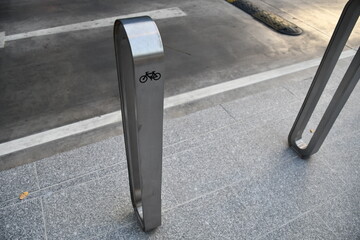 Aluminum Bicycle parking rack or bicycle stand near the road side with bicycle sign,  a device to which bicycles can be securely attached for parking purpose . modern style for city.