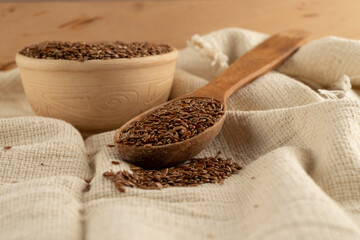 Flax seeds in a wooden spoon on a linen tablecloth. Village flavor. Natural food.