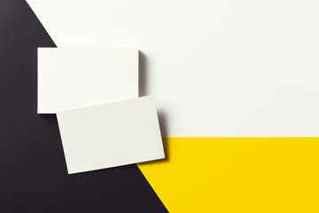 White business card on black, yellow and white background.