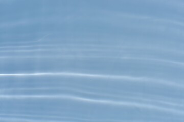 Blue water with ripples on the surface. Defocus blurred transparent blue colored clear calm water surface texture with splashes and bubbles. Water waves with shining pattern texture background.