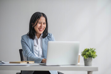 Young smiling Asian business woman employee working on laptop in corporate office. Happy professional businesswoman marketing manager using computer technology