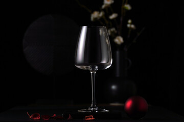empty wine glass on the table with black background, flower in a vase, beverage and drink concept