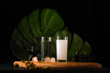 Turkish raki drink and water set on a wooden floor and dark background, ice and olive , beverage and drink concept