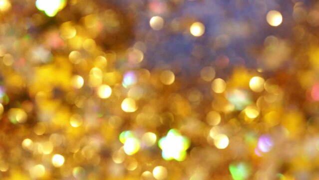 Abstract gold background of falling blurry glitters and stars. Gold sequins and stars defocused background. Bokeh effect. 