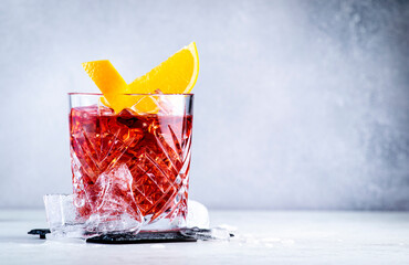 Negroni alcoholic cocktail drink with dry gin, red vermouth and red bitter, orange slice and ice...