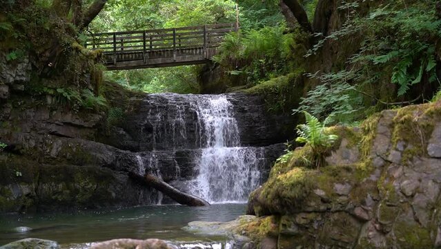 The Sychryd Cascades or Sgydau Sychryd Falls with wooden bridge in the Waterfall Country near the Dinas Rock, Brecon Beacons National Park, South Wales, UK. Slow motion calming water.
