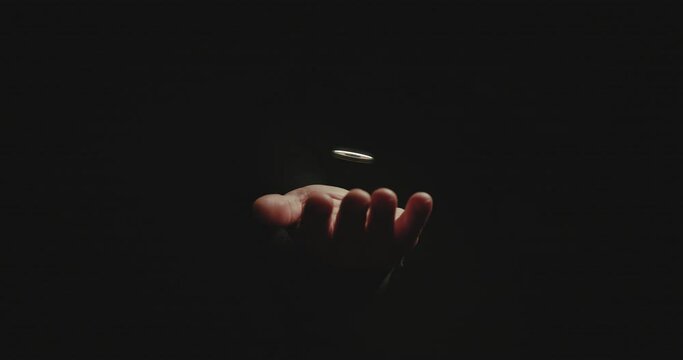 Mysterious hand in dark room offering a digital encrypted coin