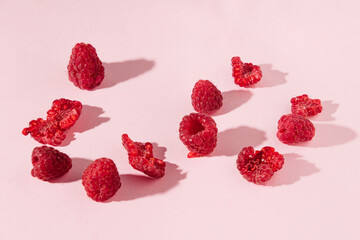 Raspberries on pastel pink background, creative summer berry fruit layout. 