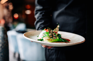 waiter hand hold Fried salmon steak, cream cheese and steamed pak choi cabbage