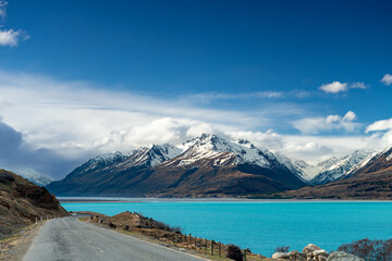 Scenic view at Mount Cook Road alongside Lake Pukaki with snow capped Southern Alps basking in the late winter evening light. Best road trip route in New Zealand South Island.