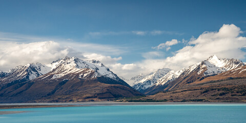 Scenic view at Mount Cook Road alongside Lake Pukaki with snow capped Southern Alps basking in the late winter evening light. Best road trip route in New Zealand South Island.