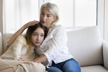 Naklejka na ściany i meble Compassionate grandmother consoling sad teenage grandkid girl, hugging kid with love, giving comfort, family support, empathy, talking to child, discussing problem, depression