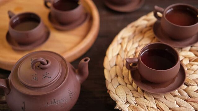 Tea Ceremony. Traditional Asian Tea Utensil, Serving Authentic Set. Person Pouring Tea from Brown Pottery Teapot to Teacup. Bamboo Tray. Lifestyle. Wellness Balance Health. Tea Brewing Equipment