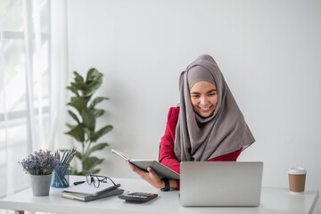 Portrait of beautiful muslim businesswoman smiling at the camera, sitting at her desk.