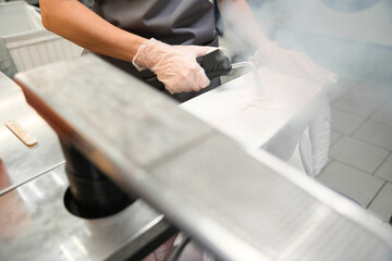 Dry-cleaning service worker treating clothing with steam