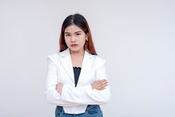 An irked and irritable young woman glaring at the camera with arms crossed. Isolated on a white background. - obrazy, fototapety, plakaty