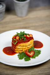 Omelets are stacked in layers. topped with tomato sauce Garnish with peppers and tomatoes.