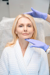 Hands in medical gloves holding woman head