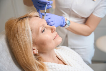 Obraz na płótnie Canvas Close up of adult woman getting antiwrinkle injection at cosmetologist