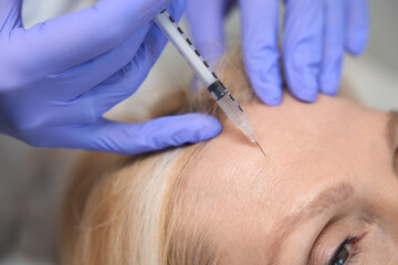 Close up of adult lady getting antiwrinkle forehead injection