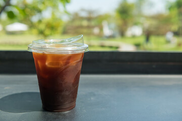 Ice americano coffee on table with spring garden view of outdoor cafe