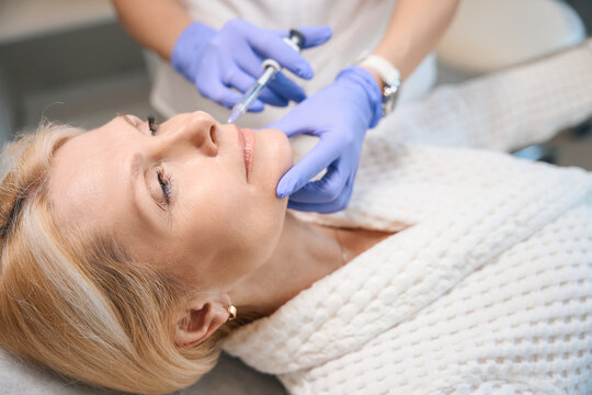 Adult lady getting face injection in beauty salon