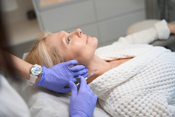 Adult lady getting neck injection in beauty salon - obrazy, fototapety, plakaty