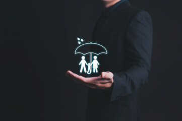 family (father, mother, son and daughter) under umbrella in man hand, Insurance concept.