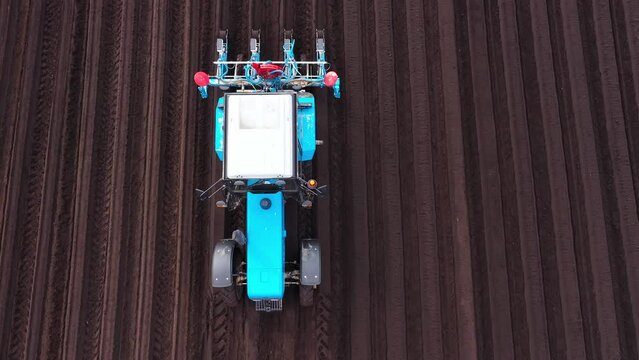 Tractor sowing seeds with a seeder driller in a field. Top view of tractor sowing and cultivating field.