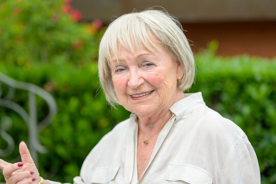 Older Woman With White Hair Pointing To The Side