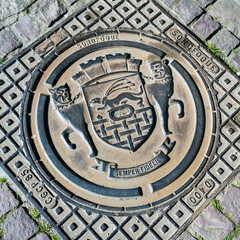  iron manhole covering with coat of arms of the town Sain Malo in Brittany, France - obrazy, fototapety, plakaty