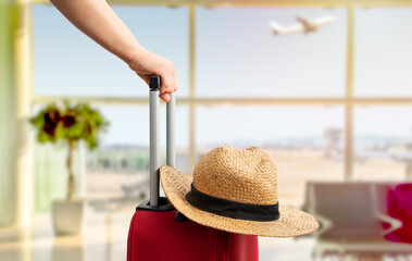 Woman with red suitcase and hat standing at airport.Tourism concept