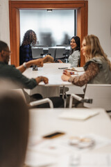 Gorgeous female employee having a conversation with her boyfriend colleague and smiling while working together lying on a recessed wall area