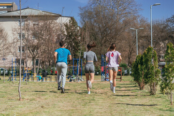Sports friends running in the park. Back view shot