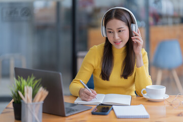 Woman using on the phone by the laptop. Working at the office, freelancing.